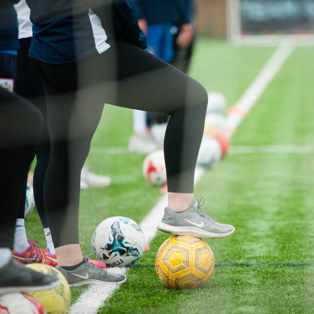 people standing with footballs on pitch sideline