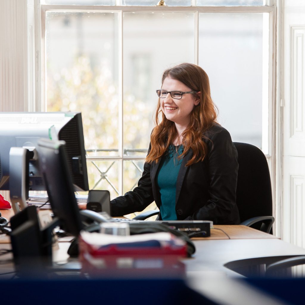 Smiling lady sitting at desk using a computer