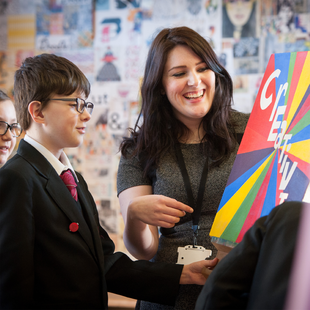 Education student on placement teaching a school pupil in an art classroom