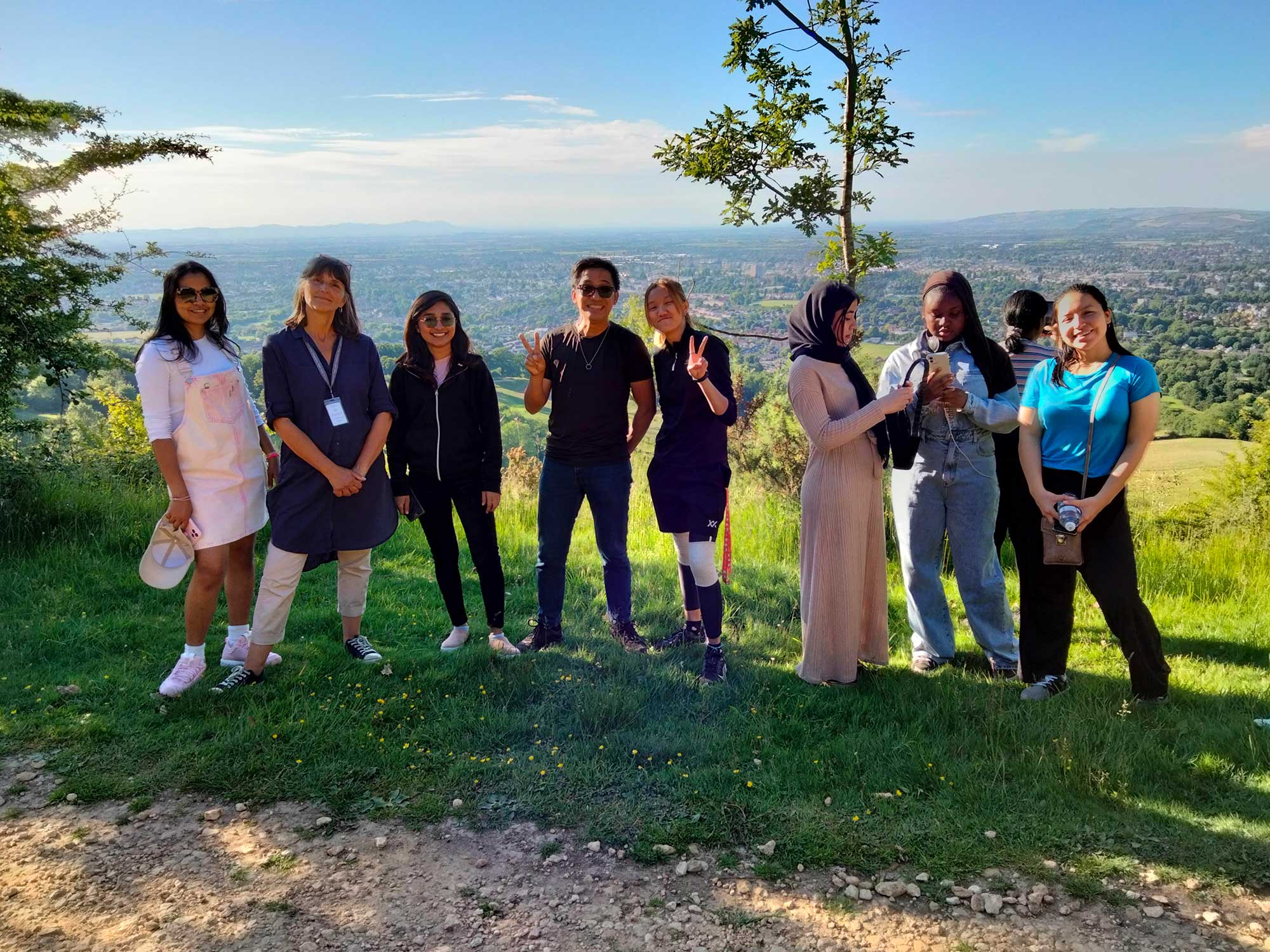 A group of students standing on Leckhampton Hill with a view of Cheltenham behind them.