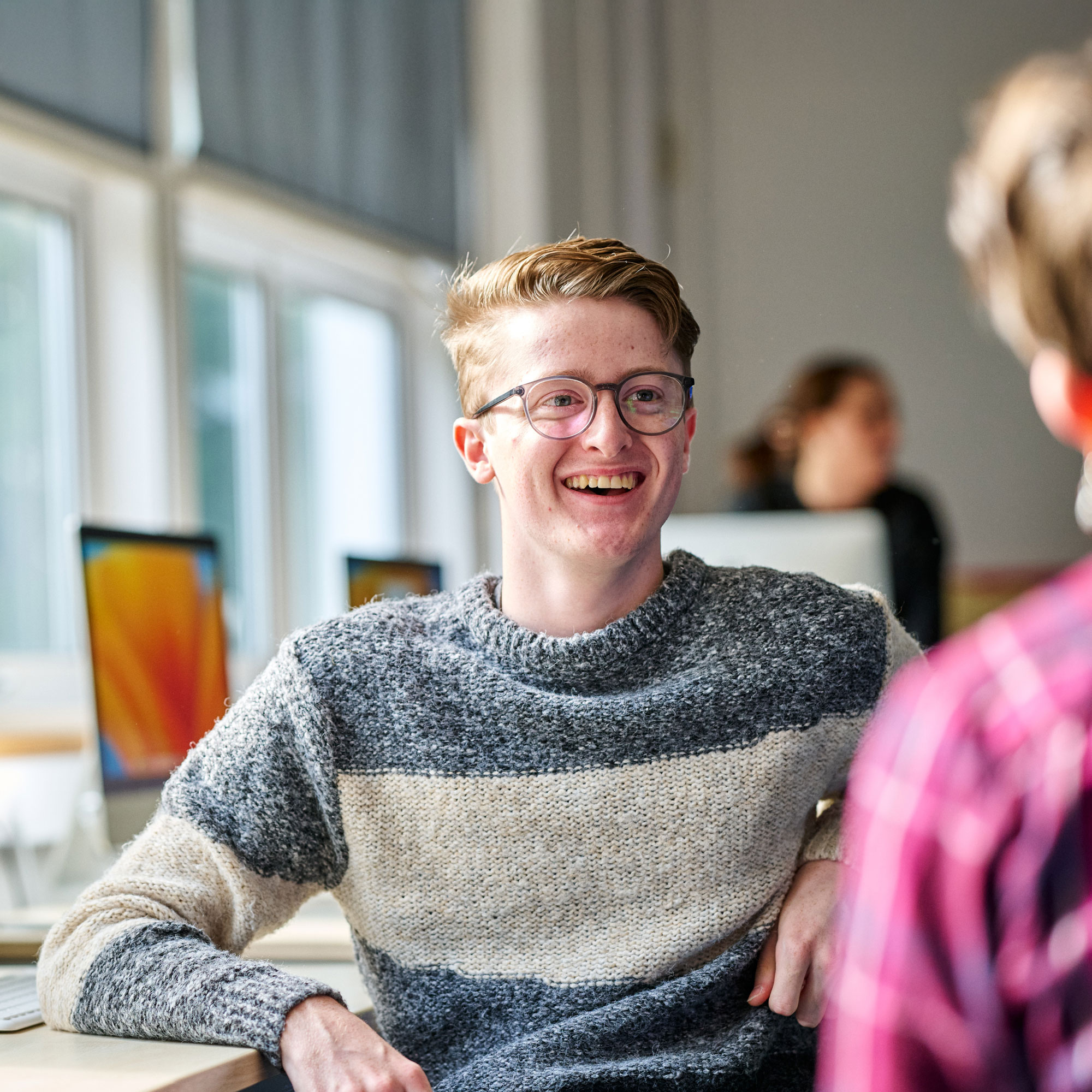 Student sat at computer smiling at camera