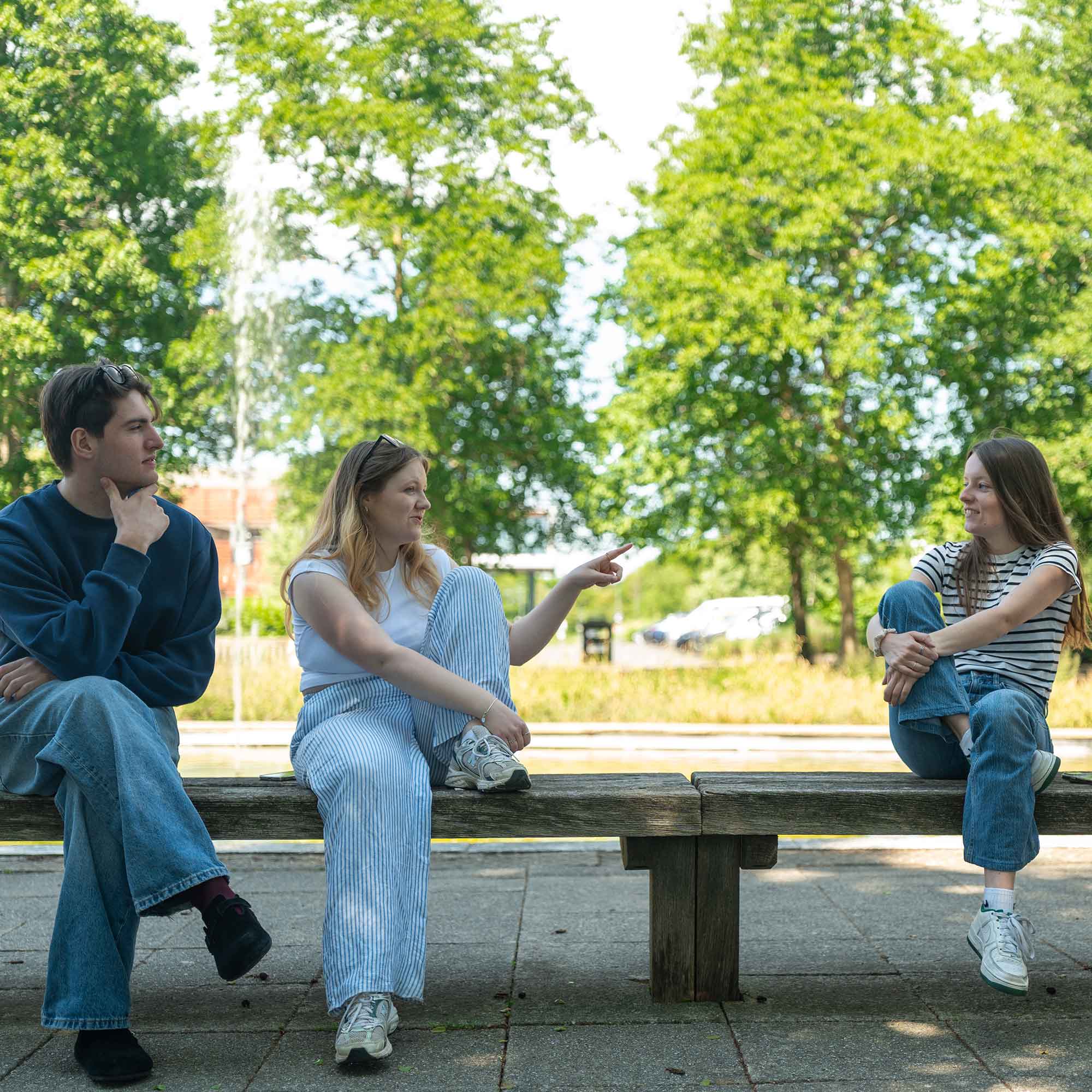 Students sat on a bench chatting at Oxstalls campus.