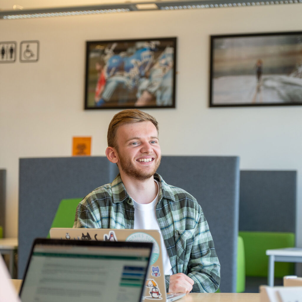 A student sat in the library smiling