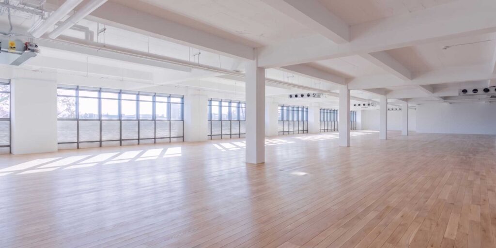 A CGI image of an empty space with wood floor and windows in the background within City Campus.